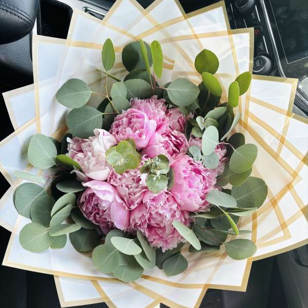 Pink peony bouquet wrapped in white paper with gold trim