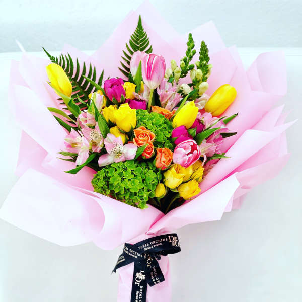 Mixed bouquet of tulips, roses, and alstroemeria wrapped in pink paper