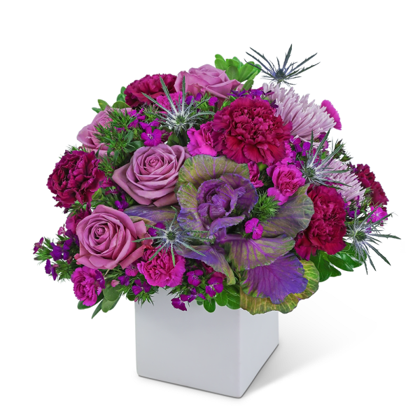 Purple and pink floral arrangement in a white square vase