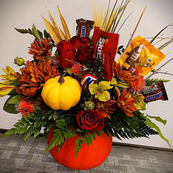 Pumpkin-shaped floral arrangement with candy bars and orange flowers