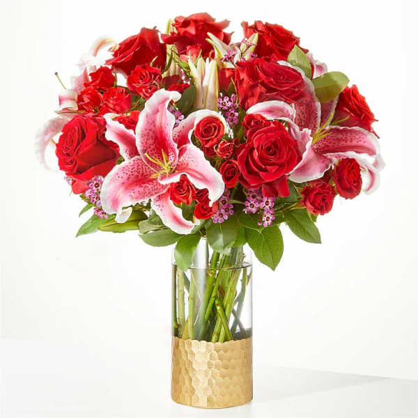 Red roses and pink lilies arranged in a glass vase
