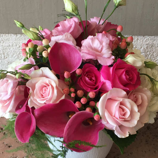 Pink roses and calla lilies arranged in a white vase