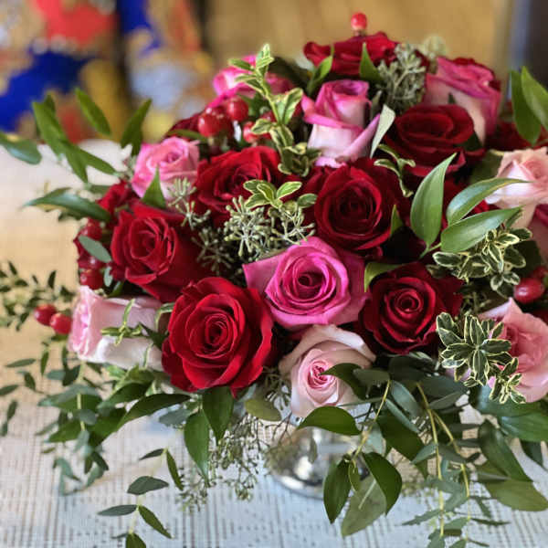 Bouquet of red and pink roses with greenery in a glass vase