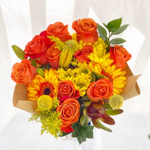 Bouquet of orange roses and yellow daisies wrapped in brown paper
