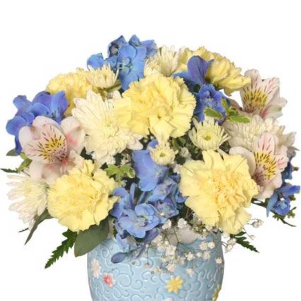Bouquet of yellow, blue, and white flowers in a light blue vase