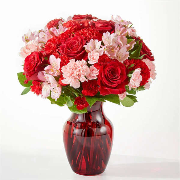 Red roses and pink carnations in a red glass vase