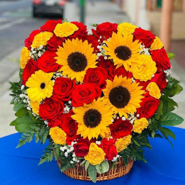 Heart-shaped basket arrangement of red roses and yellow sunflowers