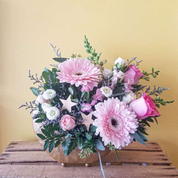 Pink gerbera daisies and roses in a low gold vase