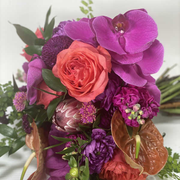 Bright bouquet with a coral rose, purple orchids, and orange anthuriums