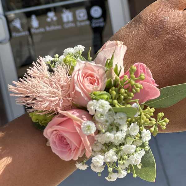 Pink rose wrist corsage with white baby's breath and green accents