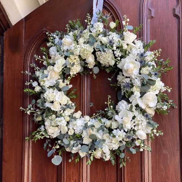 White floral wreath with roses on a wooden door