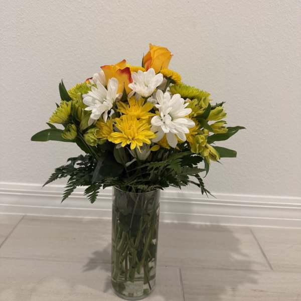 Yellow and white flower bouquet in a clear glass vase