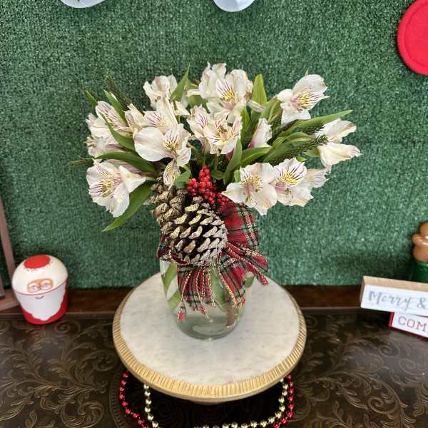 White alstroemeria bouquet in a glass vase with pinecones and plaid ribbon