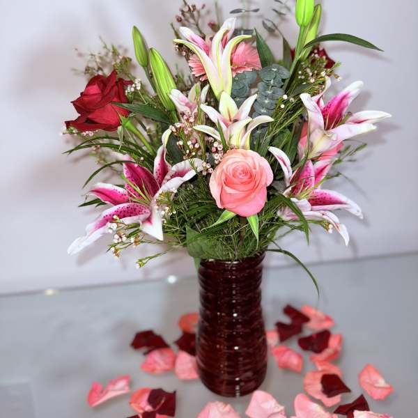 Bouquet of pink lilies and roses in a red glass vase