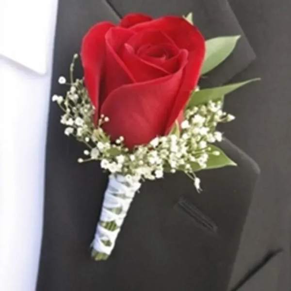 Red rose boutonniere with small white accent flowers pinned to a black suit lapel