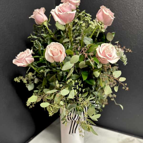 Pink roses in a white vase with airy greenery