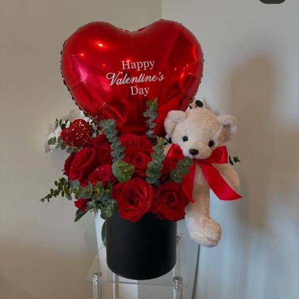 Red rose arrangement with a heart balloon and teddy bear in a black box
