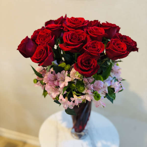 Bouquet of red roses with pink filler flowers in a glass vase