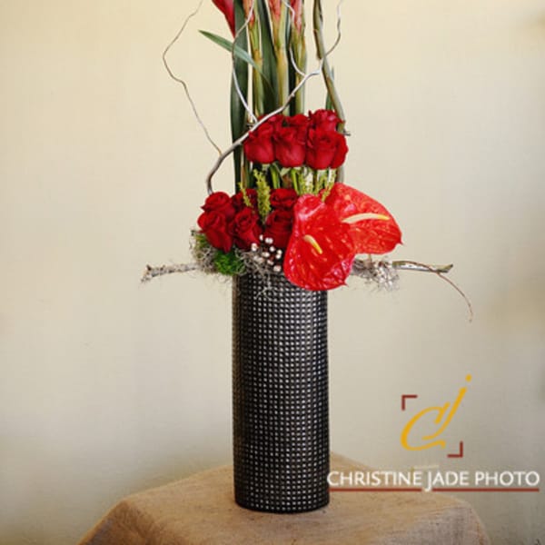 Tall red floral arrangement in a black textured vase