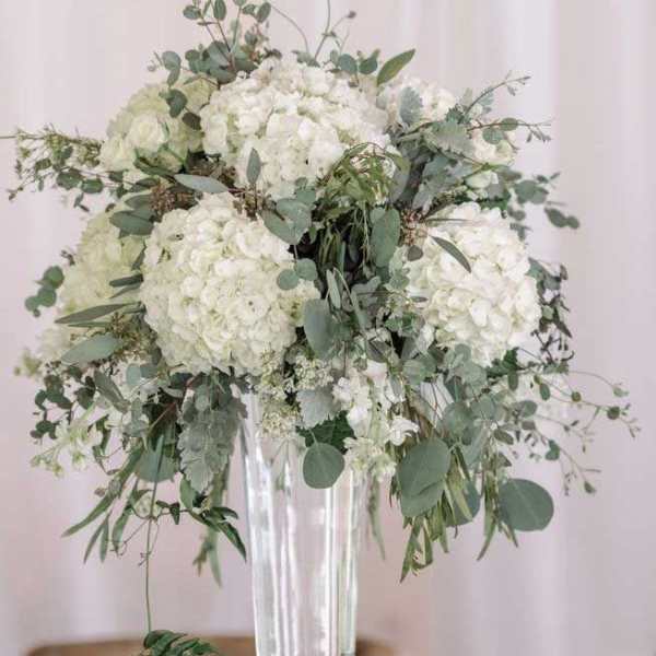 White floral centerpiece in a tall clear vase