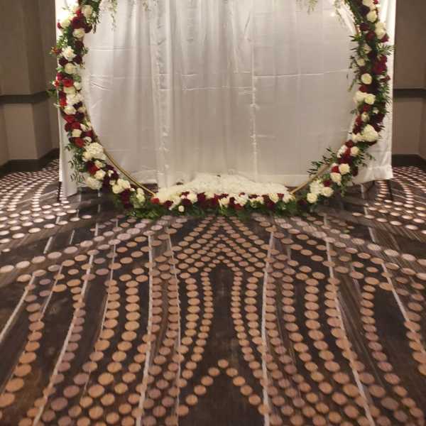 Large floral arch with red and white roses in front of a white backdrop