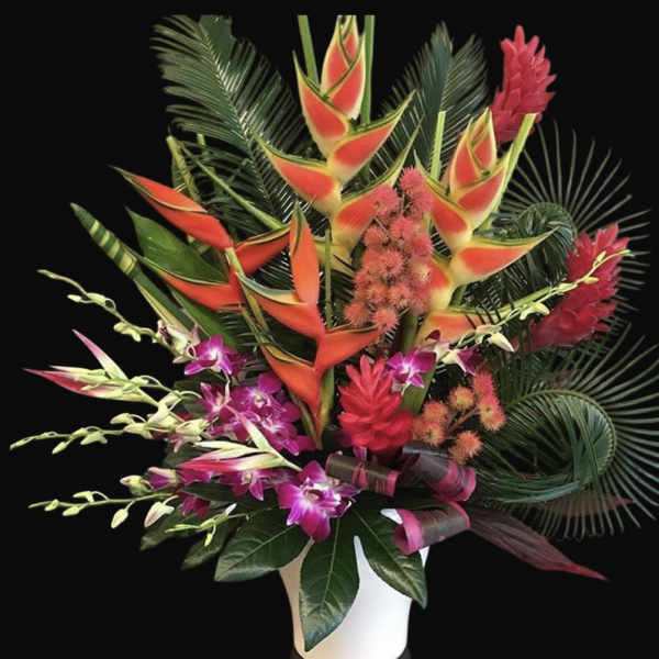 Tropical bouquet with orange heliconia and purple orchids in a white vase