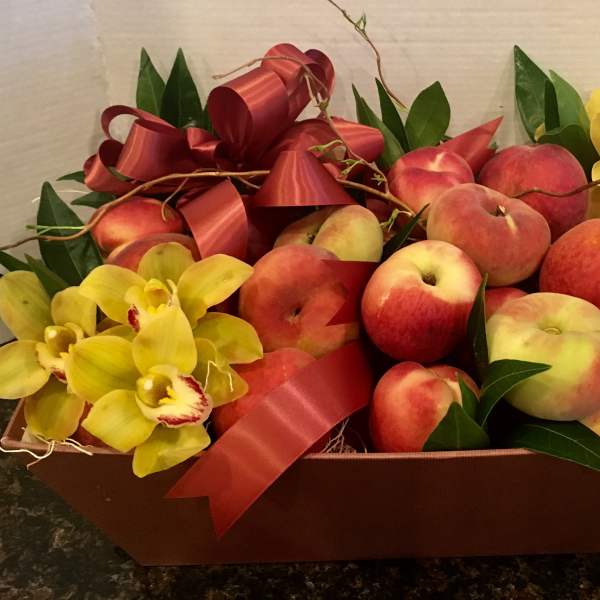 Fruit gift basket with peaches and yellow orchids in a brown tray