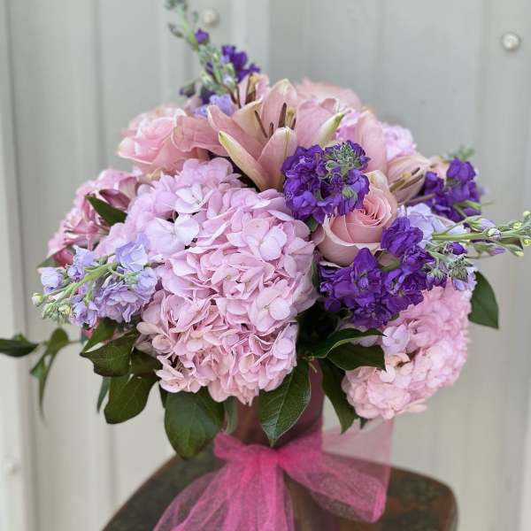 Pink and purple bouquet in a vase with a pink ribbon