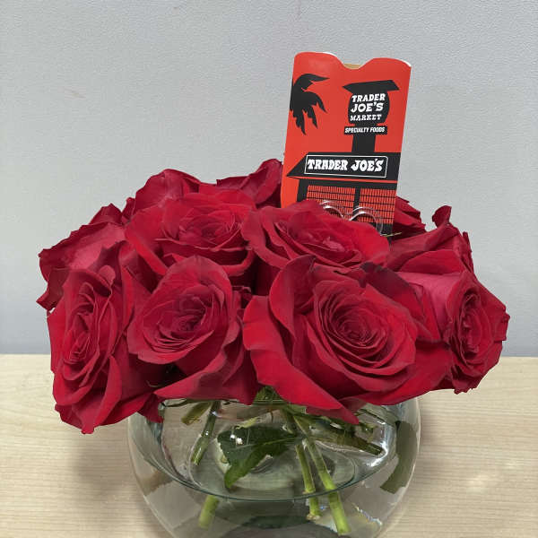 Red roses arranged in a round glass vase with a Trader Joe's tag