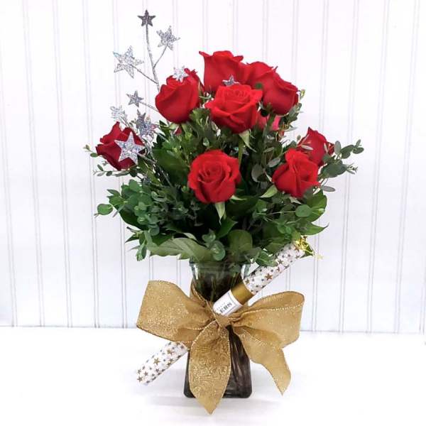 Red roses in a glass vase with a gold bow and star picks