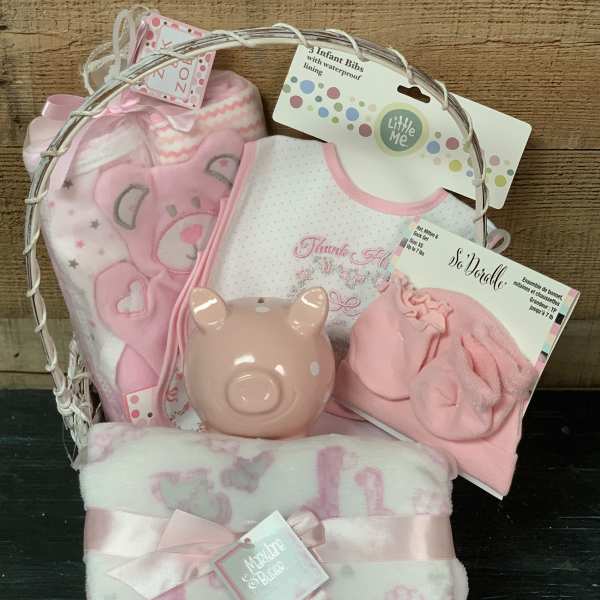 Pink baby gift basket with blankets, bibs, and a piggy bank
