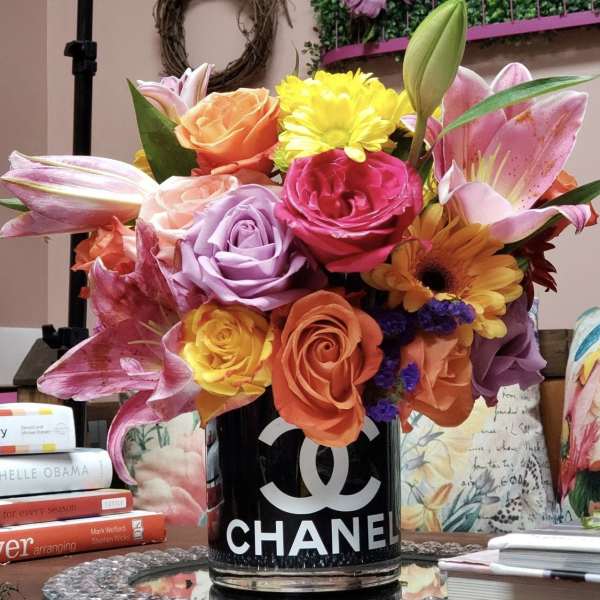 Colorful bouquet of roses, lilies, and daisies in a black Chanel vase