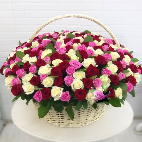 Large basket of red, white, and pink roses arranged densely in a white wicker basket