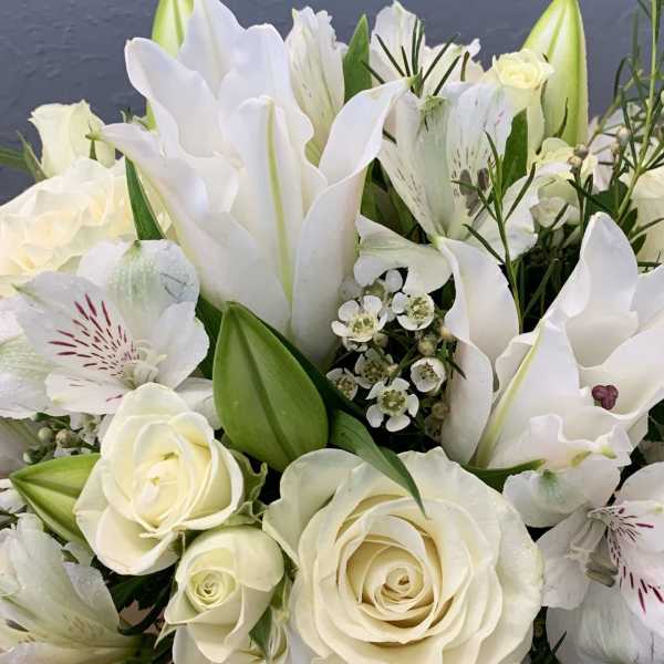 White roses and lilies in a bouquet with green buds