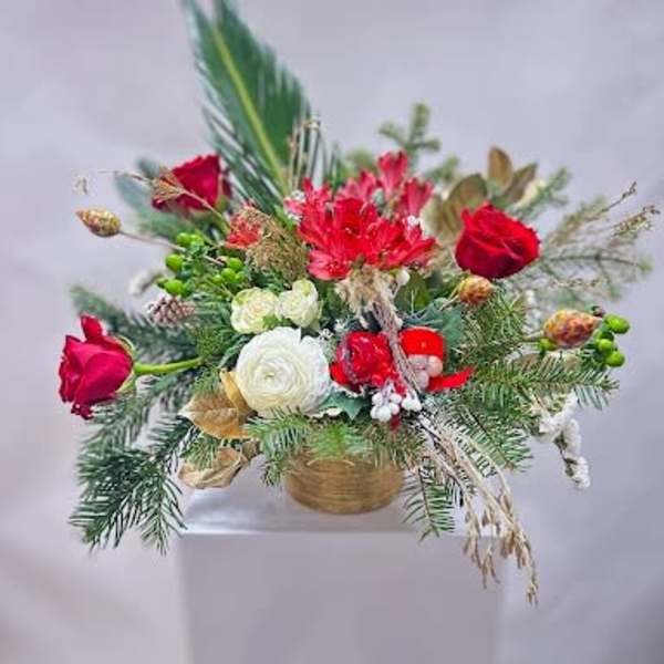 Holiday floral arrangement with red and white blooms in a gold container