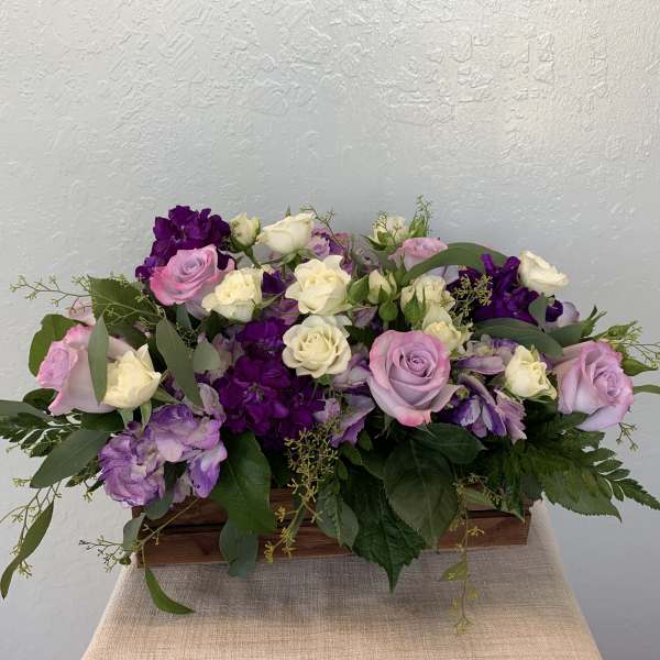 Pink, white, and purple roses in a low wooden box arrangement