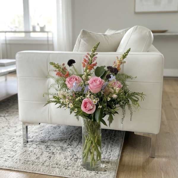Pink roses and mixed flowers arranged in a clear glass vase