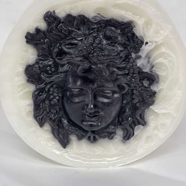Round white candle with a black sculpted face design