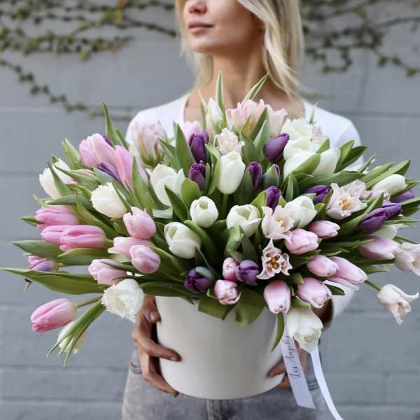 Large bouquet of pink, white, and purple tulips in a white container