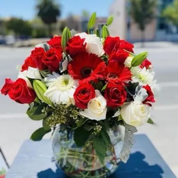 Red and white roses with white daisies in a glass vase