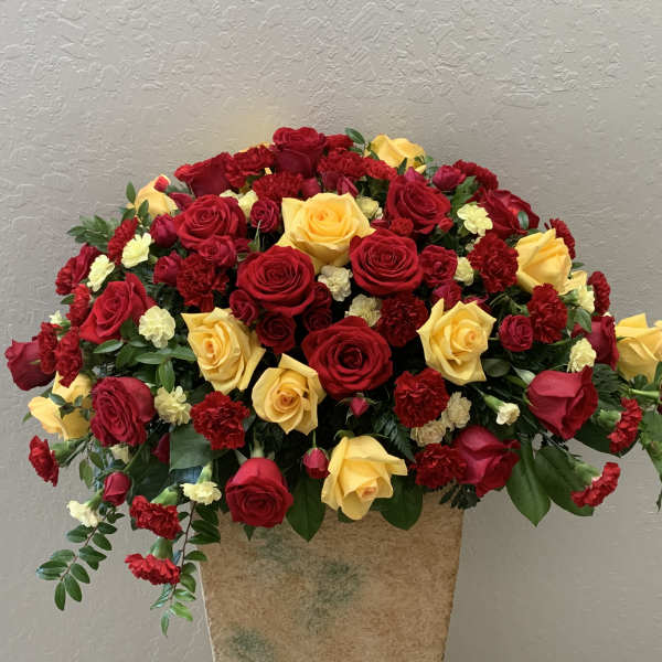 Large bouquet of red and yellow roses with red carnations in a vase