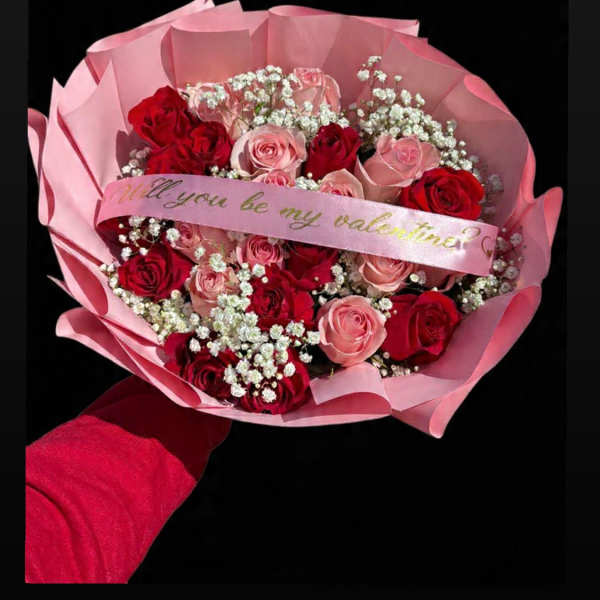 Pink and red rose bouquet wrapped in pink paper with a ribbon