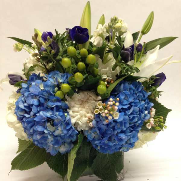 Blue and white floral arrangement in a square glass vase