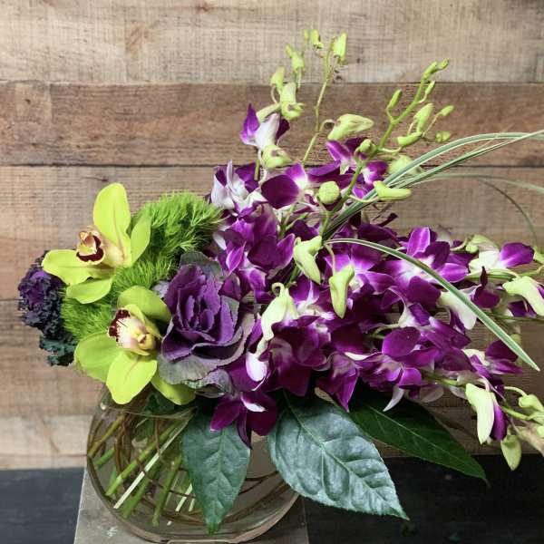 Purple orchids and green flowers in a glass vase