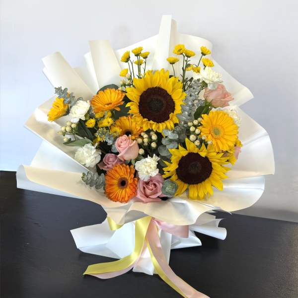Bouquet with sunflowers, orange gerberas, pink roses, and white blooms wrapped in white paper