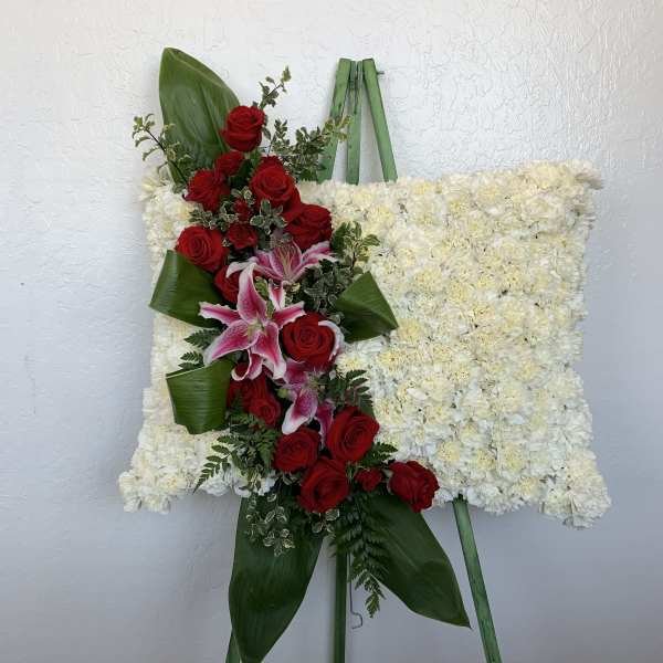 Standing floral spray with red roses and pink lilies on a white flowered easel