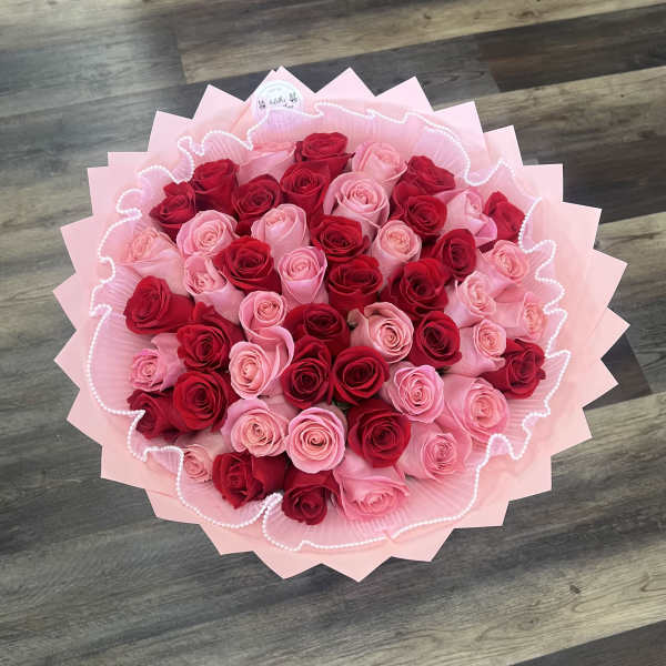 Bouquet of red and pink roses wrapped in pale pink paper