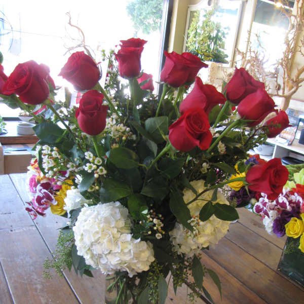 Red roses in a clear glass vase with white hydrangeas