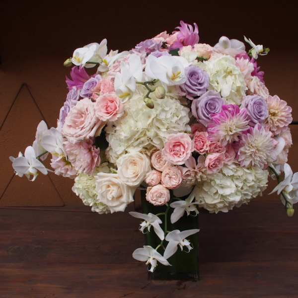 Large pastel bouquet of roses, hydrangeas, and orchids in a dark vase