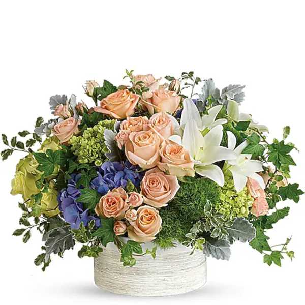 Peach roses and white lilies in a low white container